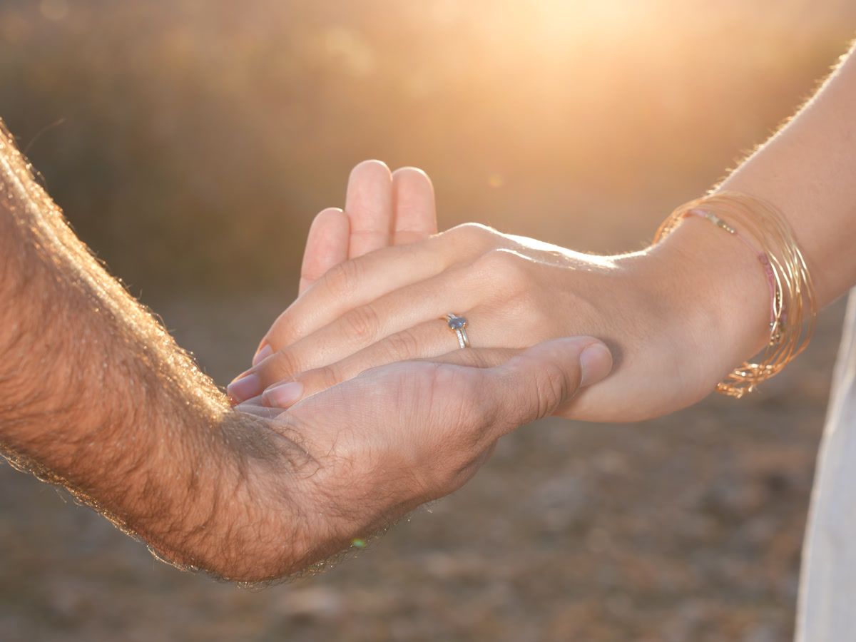 Bague de fiançailles dans la lumière dorée, le couple main dans la main à Agafay, Marrakech