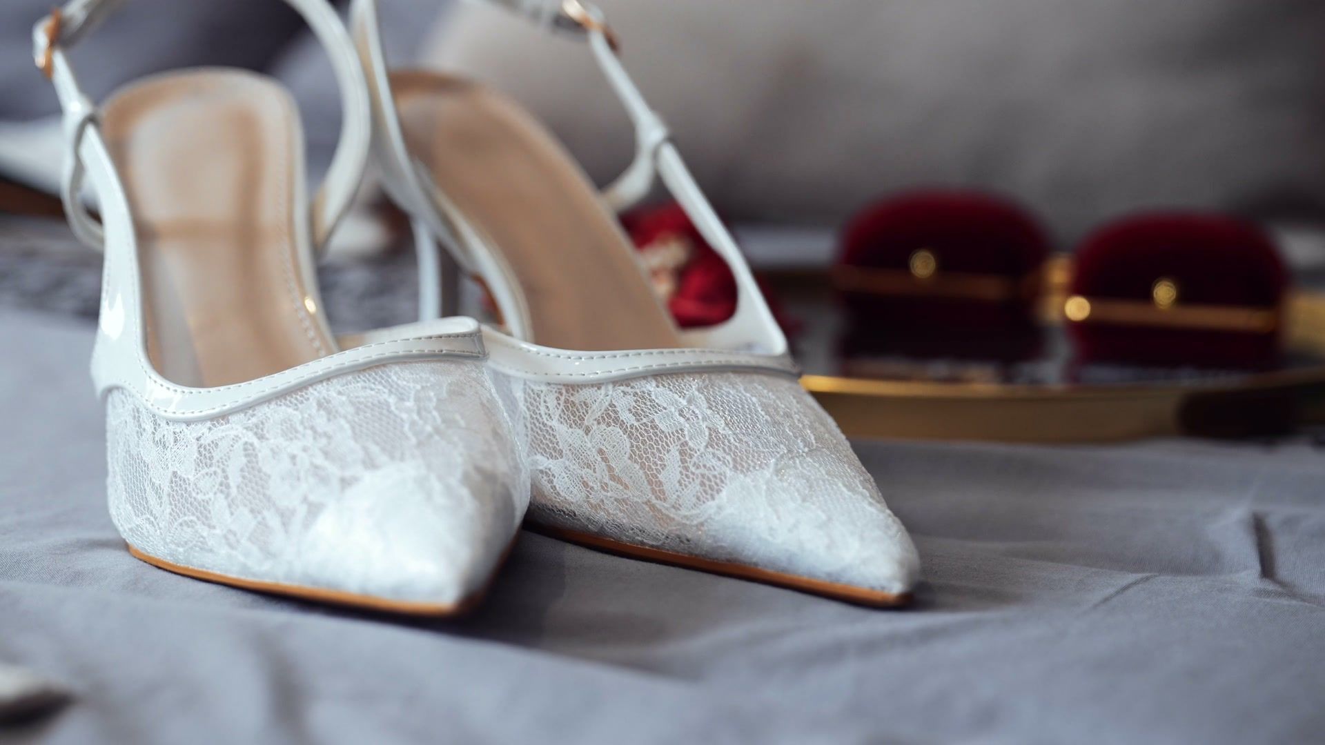 Lace bridal shoes beside the ring boxes on the wedding morning